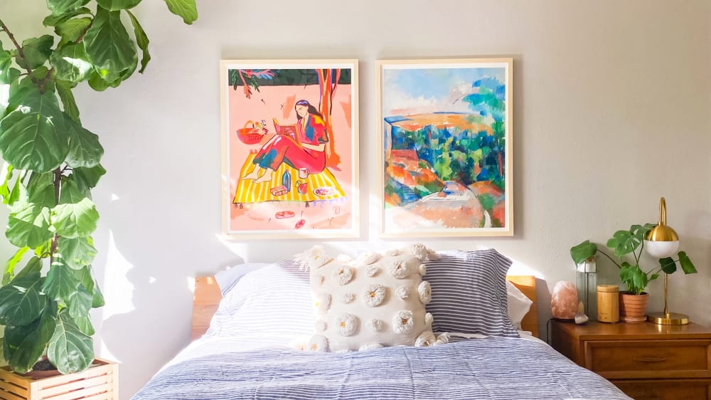 Bedroom with a tall fiddle leaf fig plant on to one side of the bed and a monstera on a bedside table